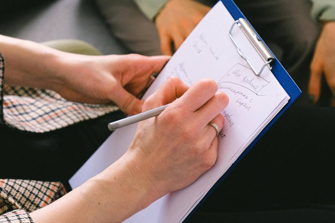 close up of hands writing on a paper on a clipboard